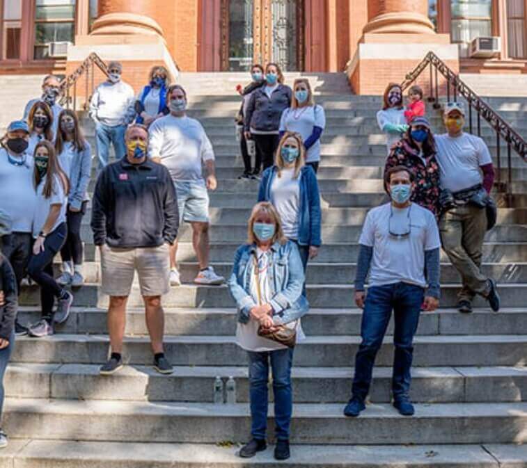 Group photo of Amylyx team standing on stairs together outdoors wearing face masks