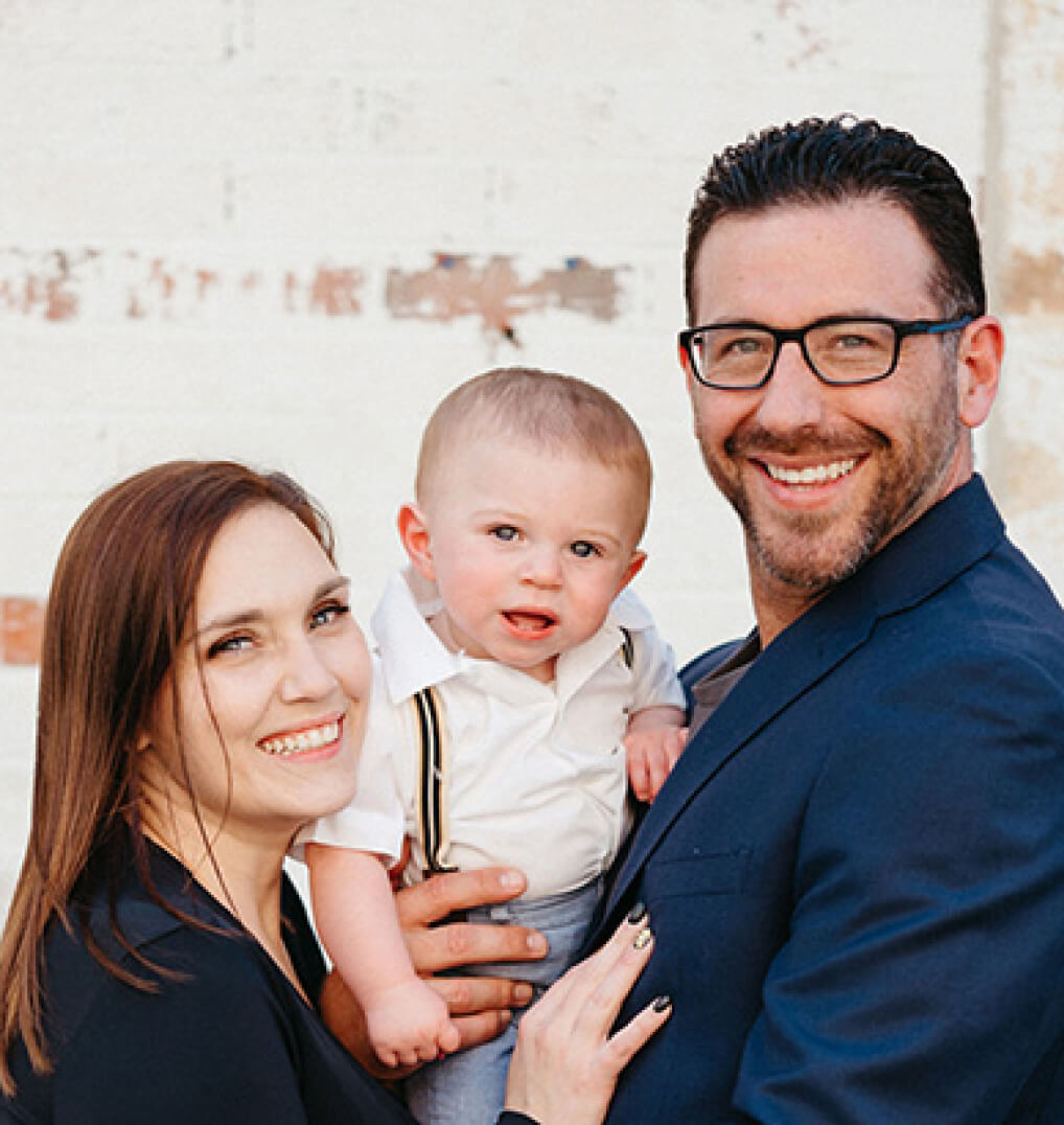 Two parents holding their toddler-age son in between them