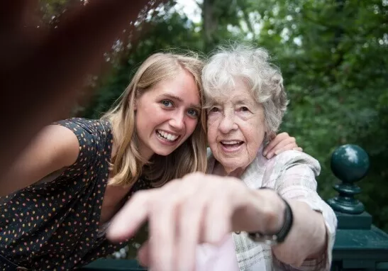 ALS patient standing with family member pointing at camera