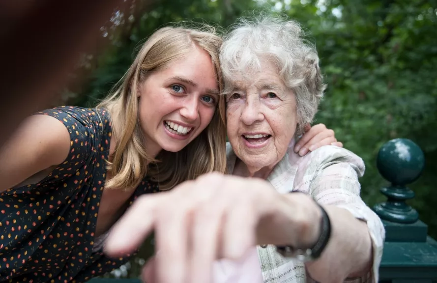 Two people smiling and pointing at camera